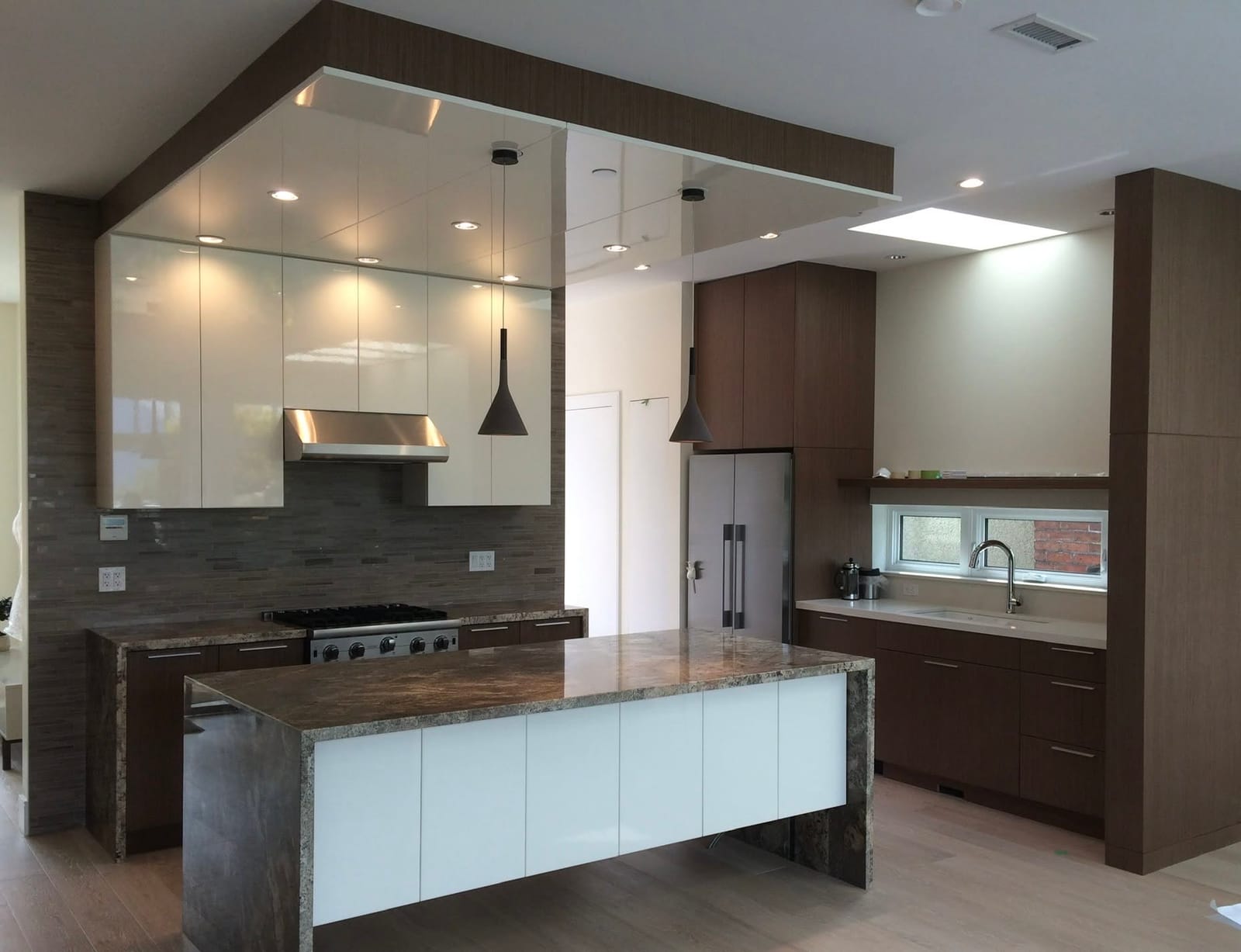 Book-matched walnut kitchen with granite-wrapped island and tile backsplash